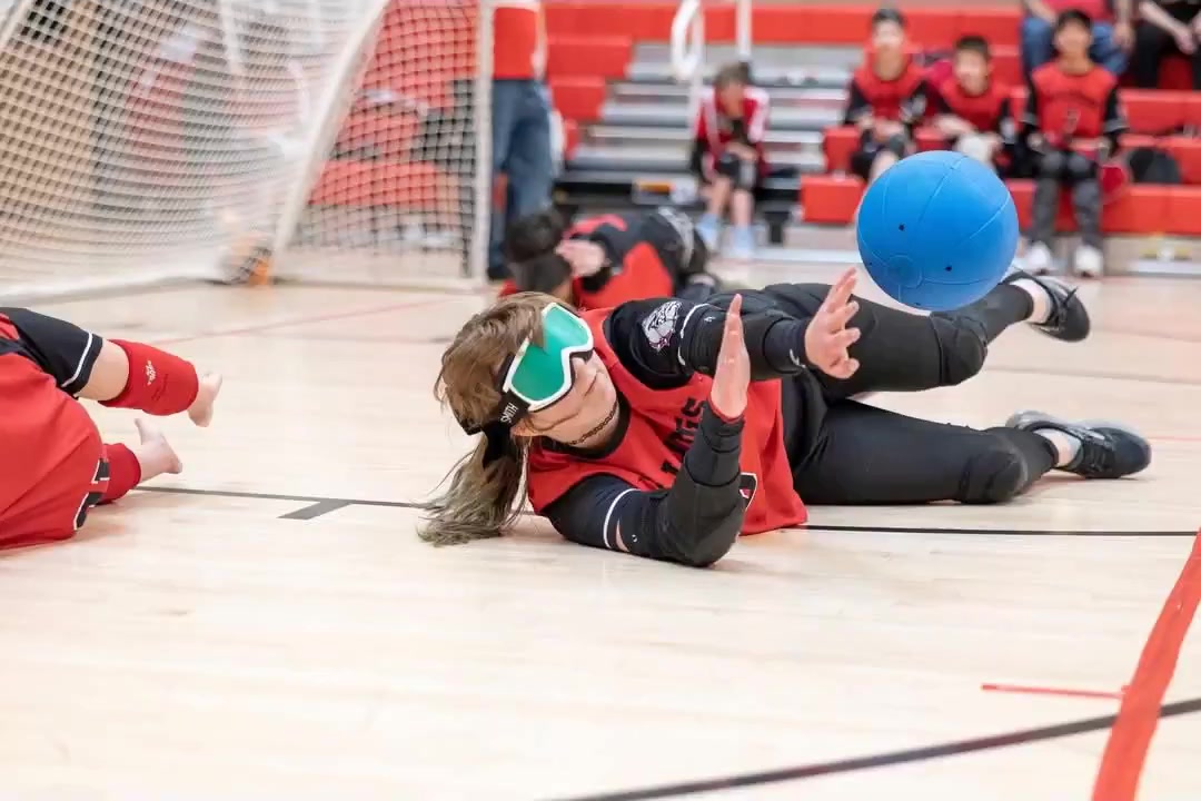 Tayler dives across the court to block the ball during a goalball match.